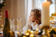 © Halfpoint - Cheerful small girl indoors at home at Christmas, sitting at table.