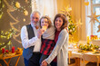 © Halfpoint - Senior couple with small granddaughter indoors at Christmas.