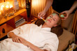 © InfiniteFlow - Serene ambiance of spa salon, woman customer indulges in rejuvenating with luxurious face cream massage with warm lighting candle. Facial skin treatment and beauty care concept. Quiescent