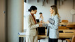 © BGStock72 - Two businesswomen shaking hands in a modern office setting during a meeting