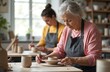 © miss irine - Elderly woman and younger person work on pottery in art studio. They shape and paint ceramic bowls, learn craft skills together. Senior woman teaches apprentice in workshop, developing creative hobby.