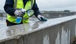© DigitalSpace - Medium shot of a worker inspecting silane weatherproof coating on concrete surfaces highlighting water repellency and enhanced durability in wet climates.