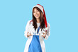 © Pixel-Shot - Female Asian doctor in Santa hat with word XMAS on blue background