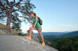 © bilanol - Sportive woman climbing alone on hillside rocky trail. Female hiker overcoming difficult cliff on wilderness path. Active lifestyle concept