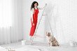 © Pixel-Shot - Happy female African-American painter in uniform with brush and cute Australian Shepherd dog on ladder during repair at home
