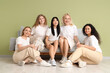 © Pixel-Shot - Group of beautiful women sitting on sofa near green wall. Women's History Month