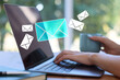 © New Africa - Woman sending or receiving email on laptop at table, closeup. Letters flying out of screen