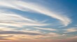 © Muksitur - Expansive blue sky with delicate, elongated white clouds gracefully sweeping across the frame, hinting at a beautiful sunset or sunrise on the horizon