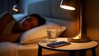 © MdEmran - Serene woman asleep in cozy bed with bedside lamp, water glass, and phone on nightstand
