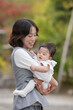 © Masakazu Tokashiki - A woman is holding a baby in her arms. The baby is smiling and the woman is smiling back. The scene is warm and loving, with the mother and child enjoying each other's company