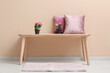 © Pixel-Shot - Pink artificial flowers with pillows on table near beige wall in room