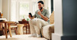 © peopleimages.com - Happy, man and fist pump with phone in home for online notification, gambling success or achievement. Person, smile and celebration in living room with tech, winning betting competition or good news.