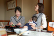 © Masakazu Tokashiki - A woman is holding a baby while another woman sits behind her. The two women are smiling and seem to be enjoying each other's company
