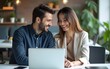 © ming - Two smiling professional business people talking using laptop computer working in office. Happy colleagues or entrepreneurs team man and woman discussing corporate technology at workplace.