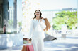 © Witoon - A cheerful young woman holding colorful shopping bags outdoors, enjoying a bright day and the excitement of shopping.