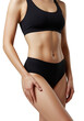 © Giuseppa - A young caucasian woman in a black athletic bralette and briefs, hand on thigh, showcasing a toned abdomen against a light grey studio background, ample copy space on left. Concept of body wellness