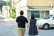 © Masakazu Tokashiki - A man and woman are walking down a street, the man is holding a bag. The woman is wearing a black dress