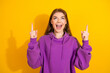 © deagreez - Young woman in purple hoodie points up with excitement against a bright yellow background for fashion lifestyle advertising