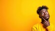 © Freshpixel - A contemplative young man, dressed in a bright yellow sweatshirt, gazes upwards against a vibrant yellow background, embodying curiosity and introspection in a modern portrait.