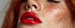 © liliyabatyrova - Close-up of a woman's face showcasing her playful freckles and striking red lips. The warm light enhances her natural beauty, creating a captivating, artistic moment