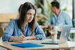 © Suteren Studio - Female Student Taking Notes from Online Lecture in Sunny University Cafeteria During Lunch