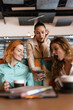 © Nikola Spasenoski - Exciting business meeting in a modern cafe with three women engaged in conversation and sharing ideas