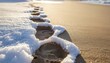 © Peyek - Footprints lead across the sandy beach covered in melting snow on a cold winter day, creating a serene and contrasting landscape.