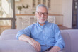 © InsideCreativeHouse - Cheerful smiling caucasian senior old elderly man with grey hair sitting relaxing on the sofa at home. Grandfather waiting for his family children friends grandchildren to visit him.