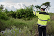 © reewungjunerr - Environmental engineer wearing safety gear collecting water sample from polluted pond for contamination analysis, environmental testing, and ecological impact assessment in natural outdoor setting.