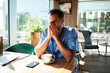 © Marko Geber - Mature male healthcare worker looking stressed in cafe