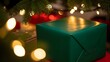 © Mas2ters - A green wrapped present under a christmas tree with bokeh lights in a festive holiday setting