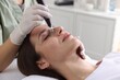 © New Africa - Woman undergoing microneedling procedure in beauty salon, closeup