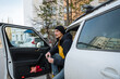 © Aleksey - urban man exiting, individual emerges from car onto city sidewalk, man dressed casually with beanie departs vehicle to run brief city errands amid buildings and parked vehicles