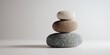© YanabY - Stacked stones create a balanced decorative arrangement on a simple white surface