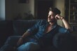 © Studicon - Pensive man contemplates the future while reclining on a sofa in a dimly lit living room