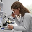 © Dece Std - Woman carefully adjusts microscope in bright, modern lab setting