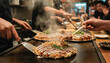 © 현욱 김 - Serving Hot Okonomiyaki to a Customer in a Lively Restaurant
