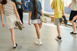 © pressmaster - Group of teenagers stretching legs during fitness class, multiethnic boys and girls standing on gym floor, lifting feet behind backs, participating in physical activity together