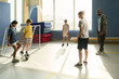 © pressmaster - Group of multiethnic children and teenagers playing soccer indoors while Black man coach supervising, children focusing on ball, sunlight streaming through large windows in background