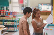 © Chocheng channel - A side view of a couple crouching down to browse items or books on low shelves in a brightly lit store or library within the mall, suggesting shared interest in shopping or reading materials.