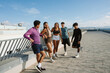 © Drobot Dean - A group of five athletes stand and laugh while two of them lean on the railing and two of them warm up