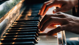 Hands playing a piano with warm lighting.
