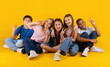 © Anastasiya - Preteen kids sitting together showing peace signs and cheerful expressions on bright yellow studio background. A playful group of children expressing joy and friendship