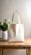 © Fauz - A cream-colored tote bag stands tall on a wooden table with a floral arrangement beside it. The natural light creates soft shadows