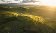© MdAyub - Aerial view of sunlit terraced fields and rolling hills under a cloudy sky at sunset agriculture