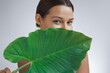 © Buyanskyy Production - Beautiful Young Woman With Glowing Skin Hiding Behind Tropical Leaf