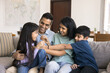 © fizkes - Happy Indian parents playing with two little son and daughter