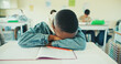 © peopleimages.com - Tired, kid and student sleeping in classroom for education, learning fatigue and boring lesson. Exhausted, child and nap on desk from study burnout, school pressure and overworked with academic exams