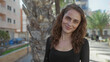 © Krakenimages.com - Woman smiling on sunny urban street with palm trees and buildings showcasing a vibrant city atmosphere.