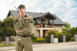 © New Africa - Security guard in uniform using radio near house outdoors. Private property protection
